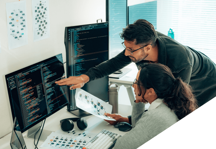 Man and woman reviewing lines of code on multiple computer screens