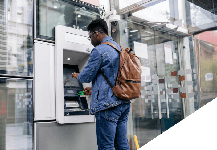 Young man using an ATM machine outside