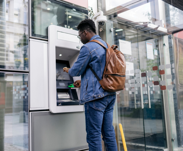 Young man using an ATM machine outside