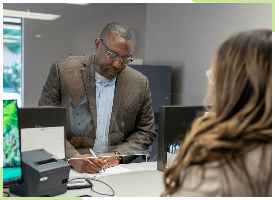 Man signing a check to hand off to a bank teller