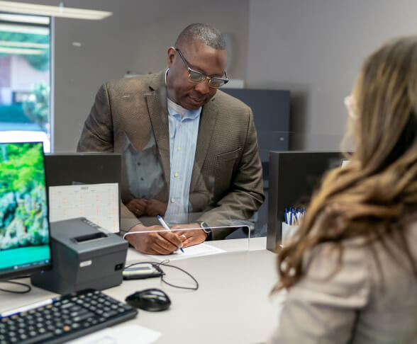 Man signing a check to hand off to a bank teller