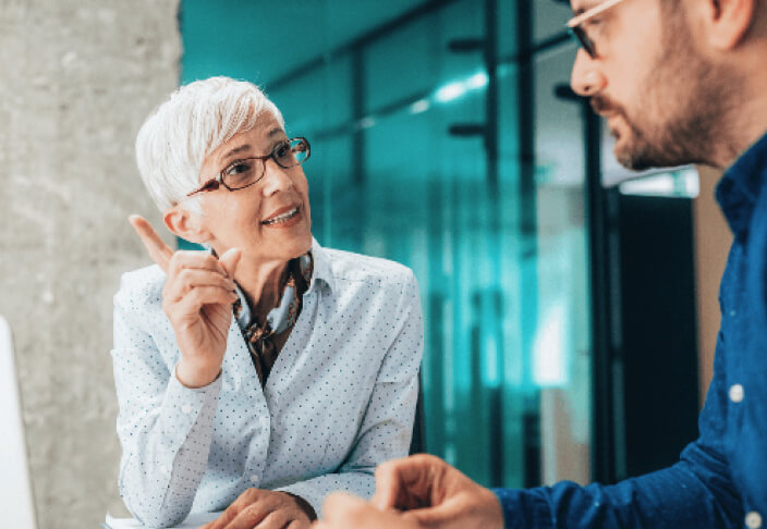 Older woman talking to younger man in professional setting