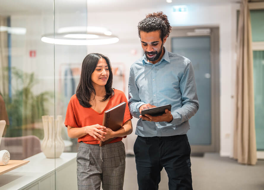 Two coworkers in office holding tablet