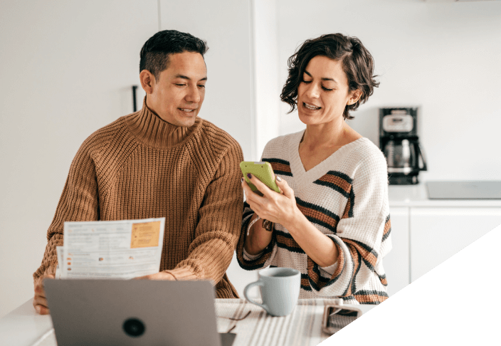 Man and woman looking at bills while sitting at the kitchen table