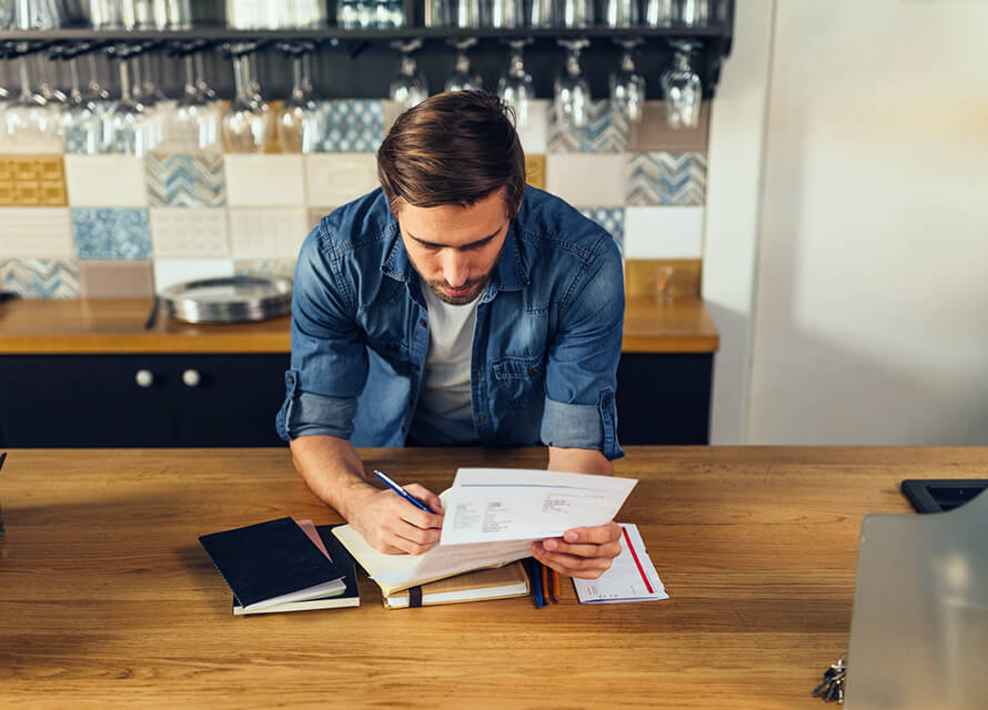 Man looking at printed documents standing behind a bar