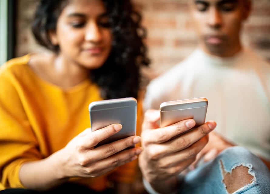 People sitting next to each other paying each other with a phone