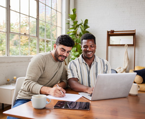 Two males looking over finances together sitting at a table with a laptop