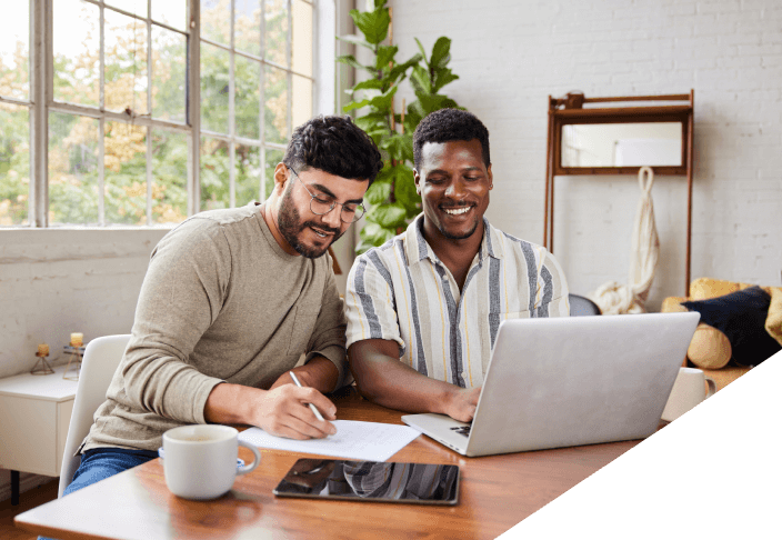 Two males looking over finances together sitting at a table with a laptop