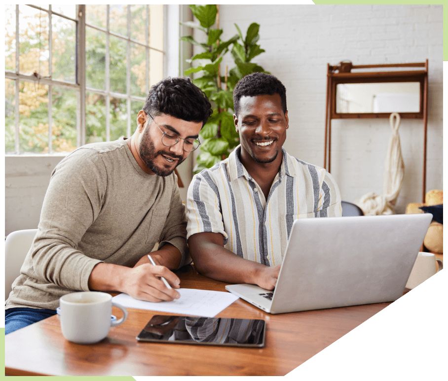 Two males looking over finances together sitting at a table with a laptop