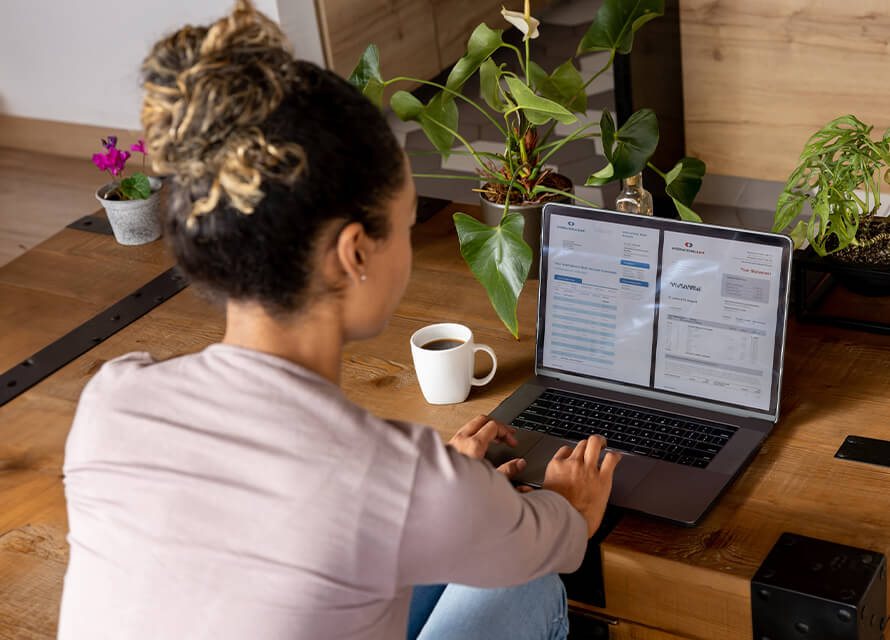 Woman looking at digital bank statements on her laptop in her living room