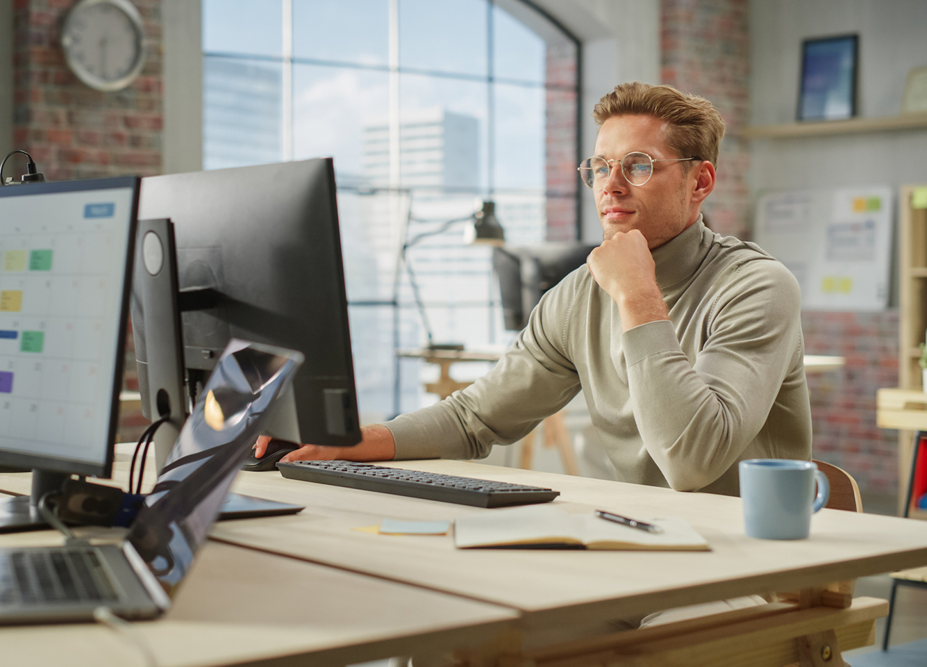 A man sits at a desk in a small business setting performing financial transactions at a computer.